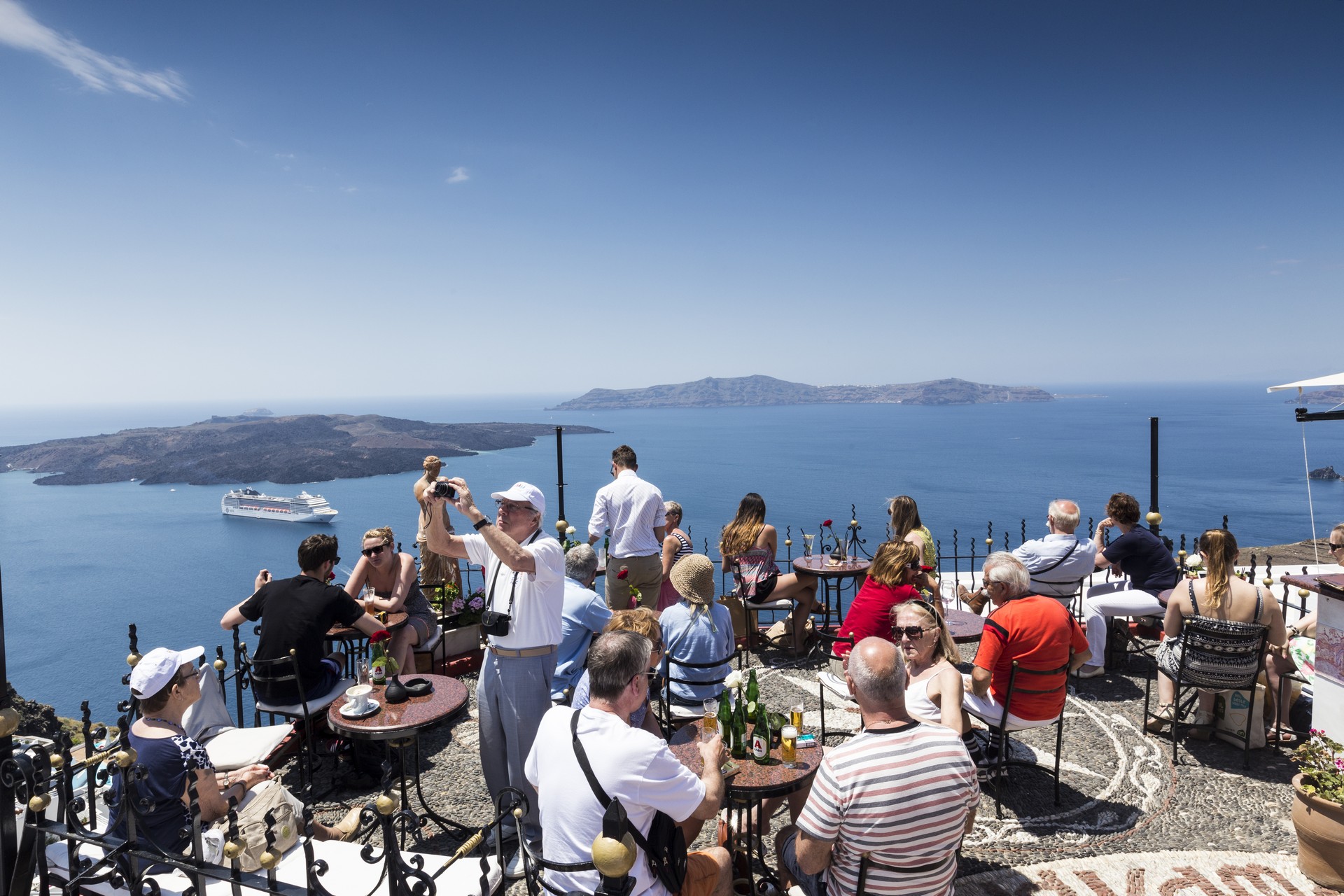Santorini, Grece- May 13, 2015: Tourists Drink beverages in Local café while enjoying the view in Santorini island, Aegean sea in Greece.